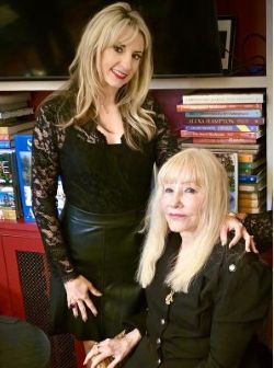 Rory standing beside Rosary (seated) in front of a bookshelf